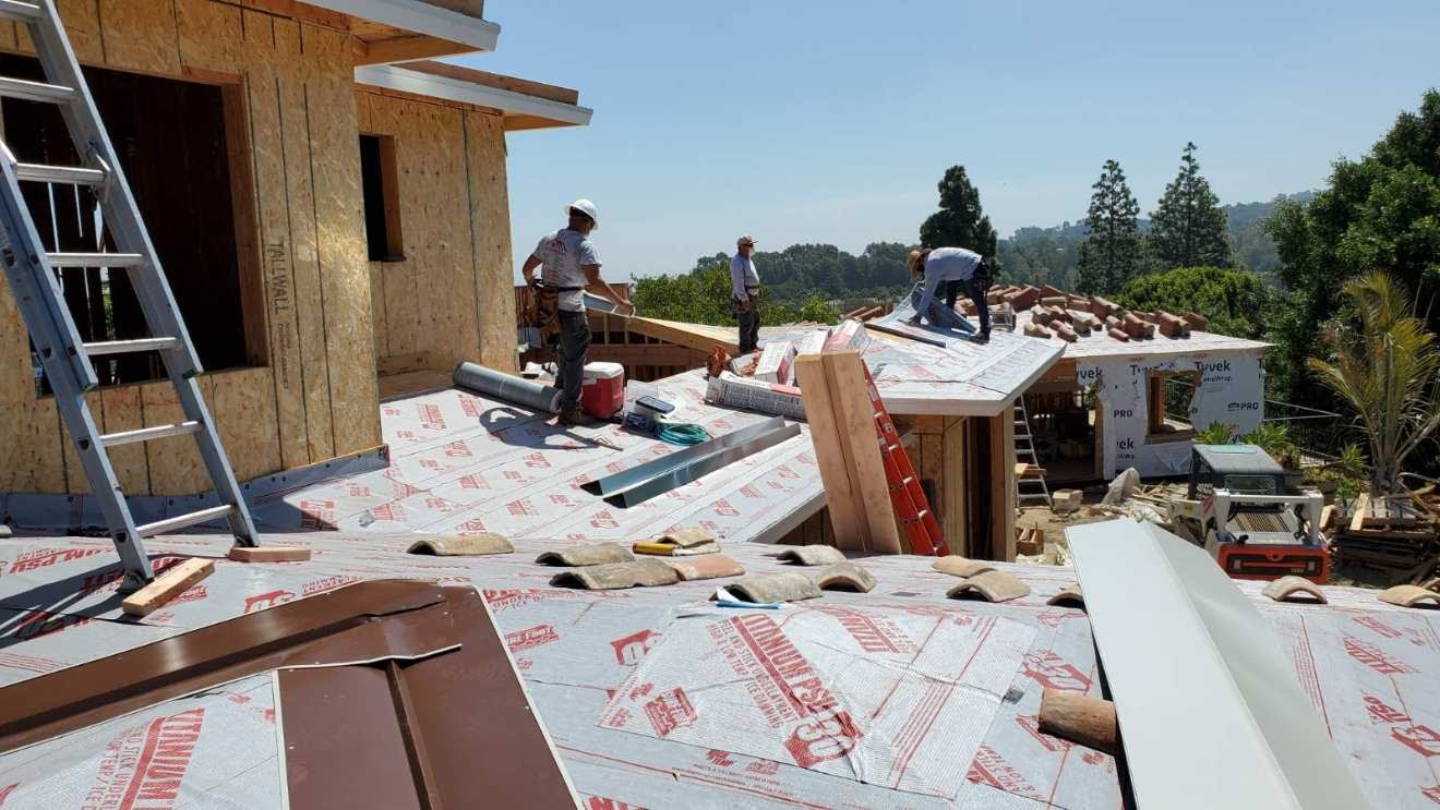 Roofers installing a tile roof over fresh underlayment on a Santa Ana area home